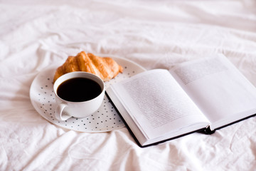 Cup of coffee with cake and open book closeup. Good morning.