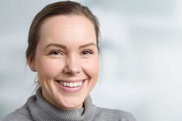 Junge Frau mit schönen Zähnen lächelt glücklich mit Zahnarztpraxis im Hintergrund