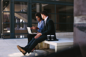 Two business people discussing work with laptop.