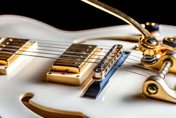 A very close view of an electric rock guitar body, strings and pickups