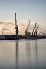 Obraz premium Cranes at work loading and unloading ships at the Port of Rotterdam