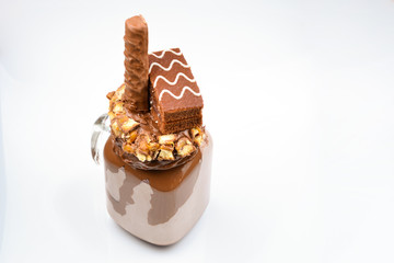 Chocolate extreme milkshake with brownie cake, chocolate paste and sweets. Crazy freakshake food trend. Copy space
