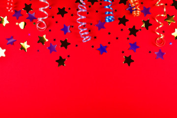 Fototapeta na wymiar Festive golden and purple stars of confetti on a red background. Space for text or design.