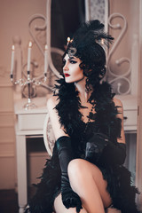 Elegante Frau im Retro-Stil der 20er Jahre, Flapper-Dame in einem schwarzen Kleid, dunklen Haaren und einem Verband, Federboa, langen Handschuhen. Bild eines Gangstermädchens auf einer Party, alte Mode. Kunst Verarbeitung
