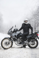 Obraz na płótnie Canvas Rider man is sitting on adventure motorcycle. Winter fun. snowy day. motorbike and snow. Enduro. off road dual sport travel tour, active life style concept. winter clothes, equipment, vertical photo