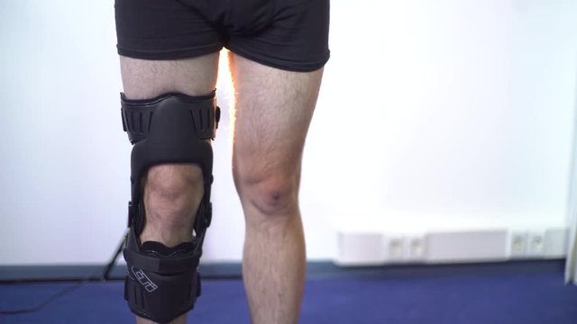 Detail of the lower half of man adjusting a supportive leg brace. Close-up shot