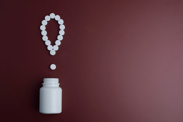 Exclamation mark of white tablets on dark red background. White pills on a red background....