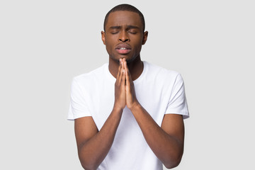 Religious black guy praying with hope isolated on studio background