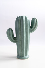 Trendy cactus shaped vases on table against light wall. Creative decor. Modern green tall ceramic vase, decoration object isolated.