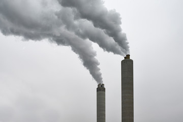Chimney of a factory blowing greenhouse gas emissions in the air 