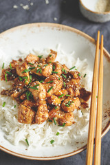 Sesame chicken pieces with rice on a ceramic plate. Chinese traditional dish.