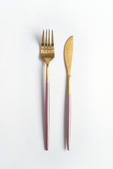 New luxury Golden cutlery view from above on a isolated white background. Top view. Pink knife and fork for a festive table for a wedding, birthday or party.