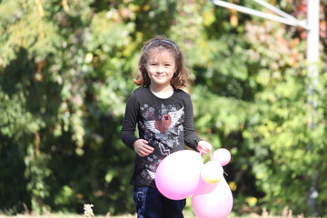 Portrait of happy smiling cute little girl child outdoors with colorful baloons