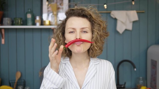 Cheerful Woman Making Moustache From Chili Pepper In Kitchen