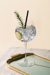 Gin tonic, an aperitif cocktail garnished with cucumber and rosemary - obrazy, fototapety, plakaty