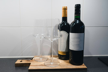 Wine bottles on a wood plate next to wine glasses 
