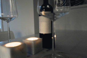 Wine bottles on a wood plate next to wine glasses. Cozy wine date.