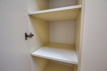 Interior of white plastic cabinet or clothing wardrobe with many empty shelves with open doors. Furniture design and installation.