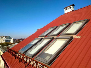 Red tiled house roof with attic windows. Roofing construction, window installation, modern...