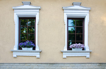 Fototapeta na wymiar Two windows and two pots with flowers on the windowsills