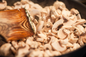 Stirring a wooden spatula with fried mushrooms