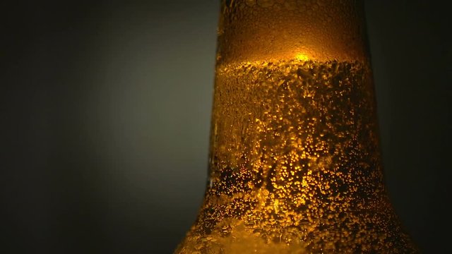Close-up golden beer color with bubbles, bottle of fresh cold beer covered with droplets, rising bubbles	