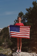 Child teenager girl holding an American flag at nature background. USA 	 resident, US citizen. Immigration concept