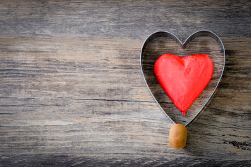 Red heart shaped chocolate in fried egg prints on wood background