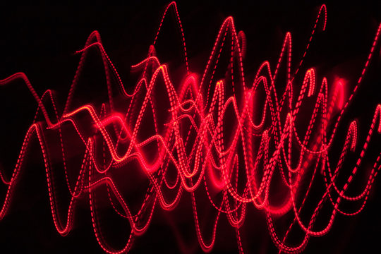 Abstract Blurred Red Light Effect On A Black Background. Long Exposure Photo Of Moving Camera