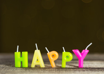 word happy assembled from wax candles of different colors