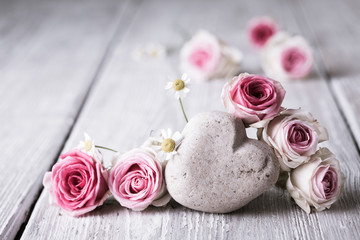 Pink roses and heart on wooden background