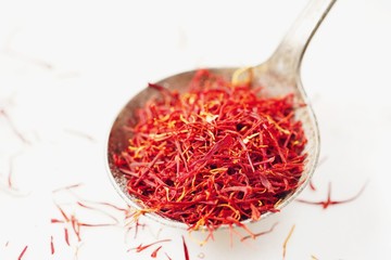 Fototapeta premium Saffron threads in a rustic spoon isolated on white