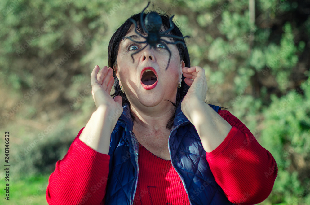 Wall mural Woman screams when she encounters a huge spider in the forest