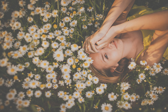 Portrait Of Young  Woman With Radiant Clean Skin Lying Down Amid Flowers On A Lovely Meadow On A Spring/summer Day