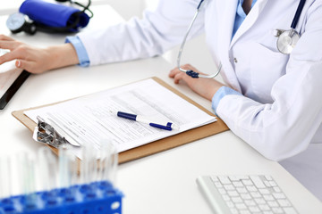 Doctor working table. Woman physician using tablet computer while sitting in hospital office close-up. Healthcare, insurance and medicine concept