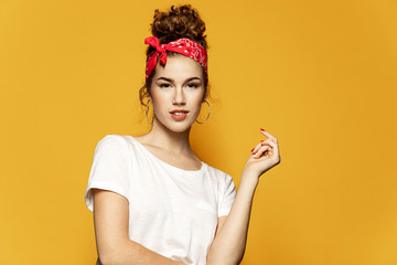 Portrait of confident brunette young woman in nice white top standing on yellow background. Charming girl with natural makeup. Copy space in right side. Retro and lifestyle concept