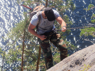 A man engaged in mountaineering. Using special equipment, he climbs the rock