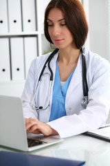 Doctor woman at work. Physician typing on laptop computer. Medicine, healthcare  concept