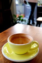 Empty cup of finished drinking coffee isolated on wooden table with blurry someone going out of the room
