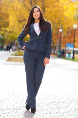 Happy arab businesswoman in blue suit walking in autumn park