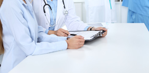 Doctor and patient discussing something, just hands at the table, white background