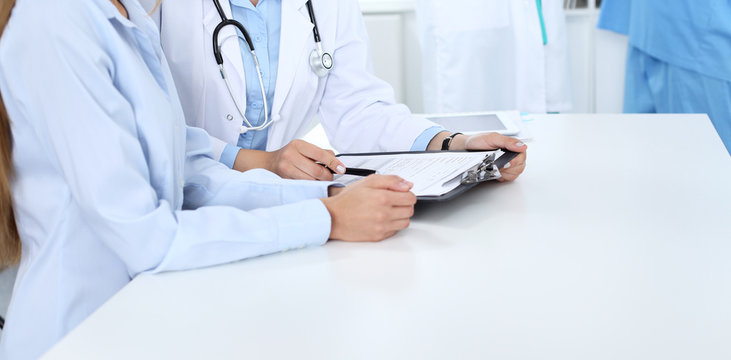 Doctor and patient discussing something, just hands at the table, white background
