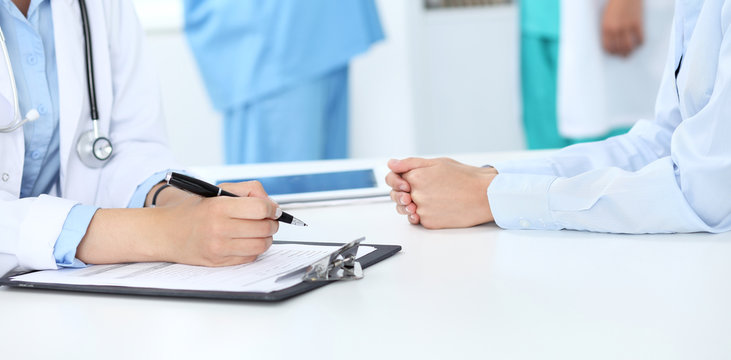 Doctor and patient discussing something, just hands at the table, white background