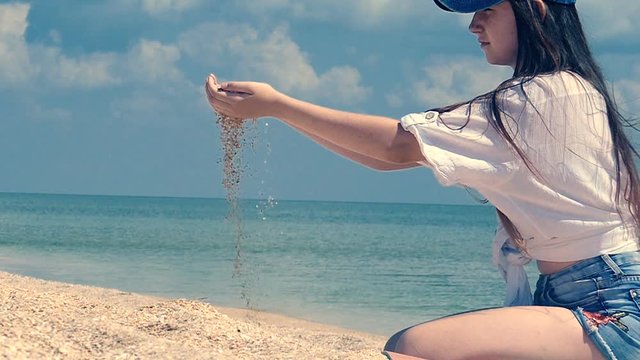 Seashore sand pouring from girl teeneger hand,  marine slow motion close up
