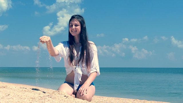 Seashore sand pouring from girl teeneger hand,  marine slow motion close up