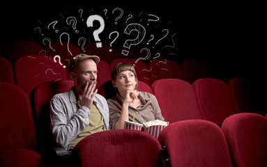 Nice couple in cinema with drawn question signs around