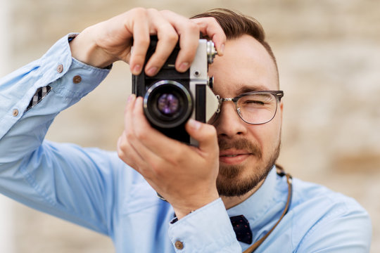 photography, technology and lifestyle - young photographer or hipster man with vintage film camera outdoors