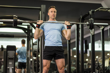 Fototapeta na wymiar Muscular man holding barbell at the gym.