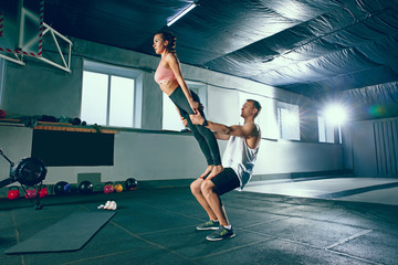 Shot of young man and woman standing in plank position at the gym. Functional fitness workout. Couple during training session. Fit athletic models. Healthy lifestyle concept