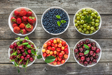 Fresh berries in a bowls. Variety of berry fruit on table, top view, flat lay.